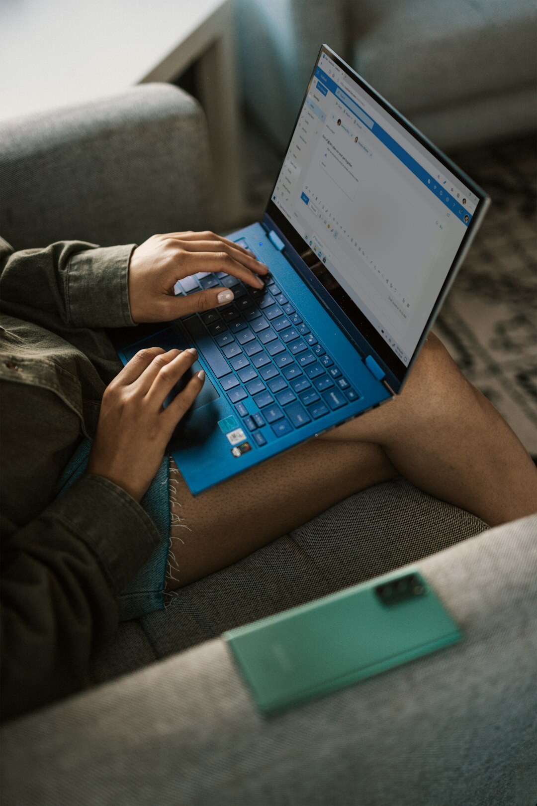 Person typing on a laptop while taking notes on a communication plan